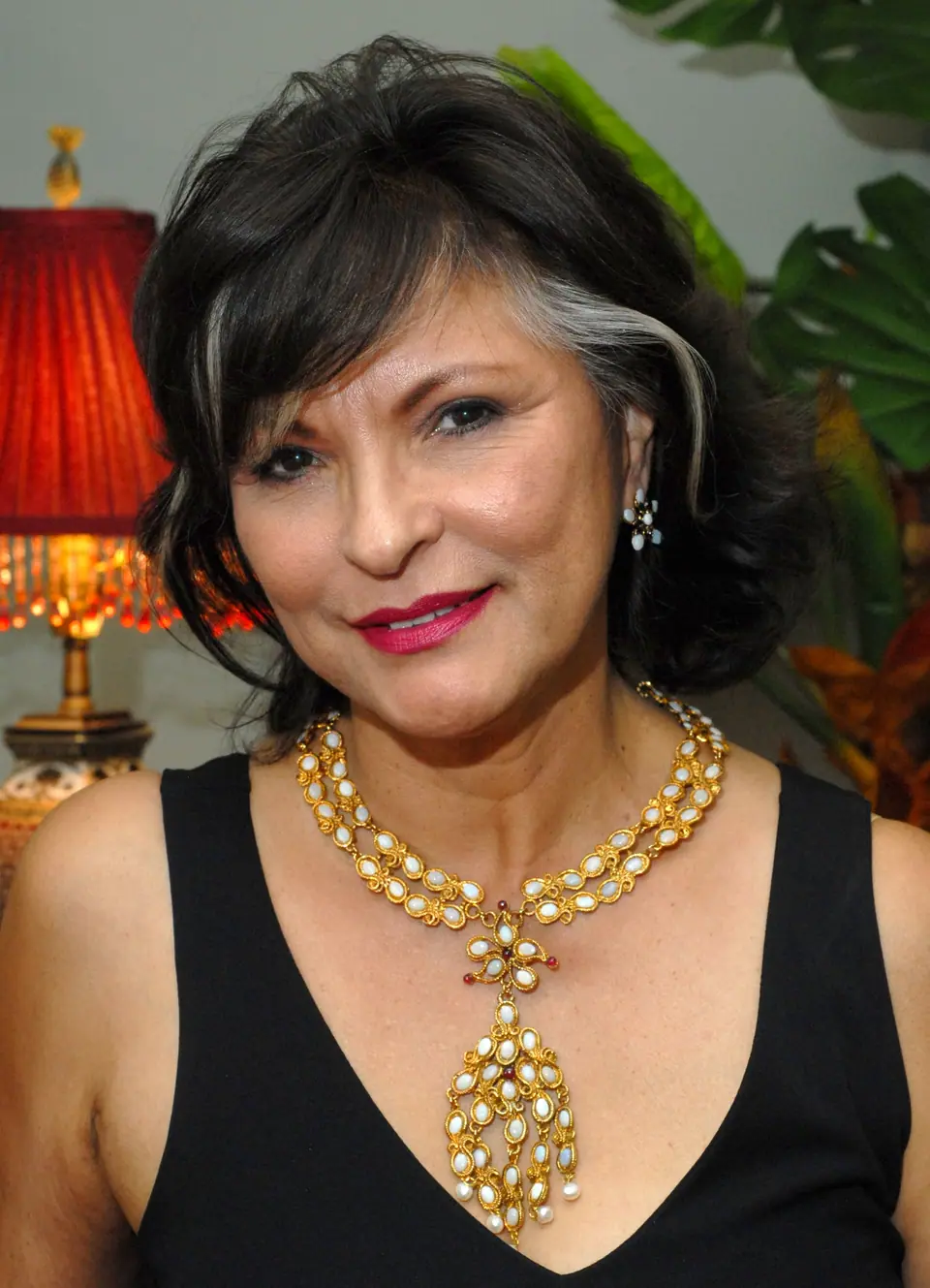 Woman in a black top wearing a gold, pearl and gemstone Swoboda statement necklace