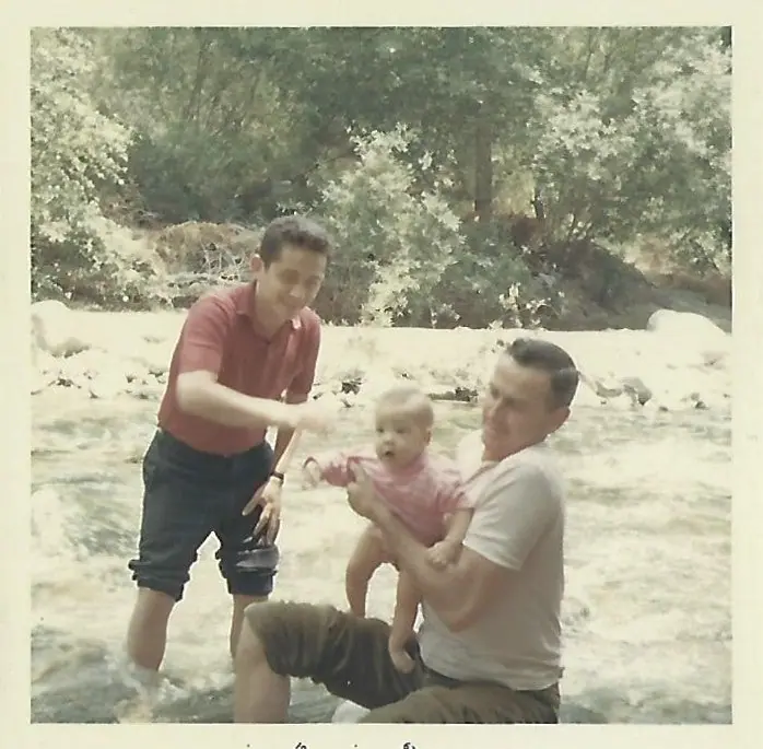 Vintage snapshot of Nate Waxman and Edward Swoboda holding a baby by a river
